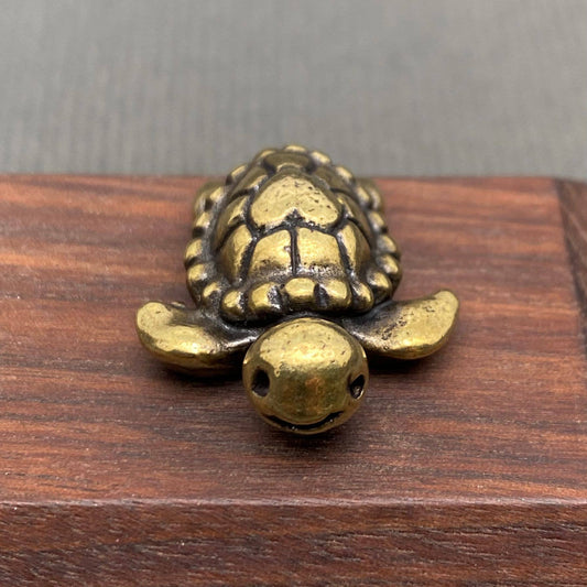 Brass figurine sea turtle on a wooden surface with a gray background