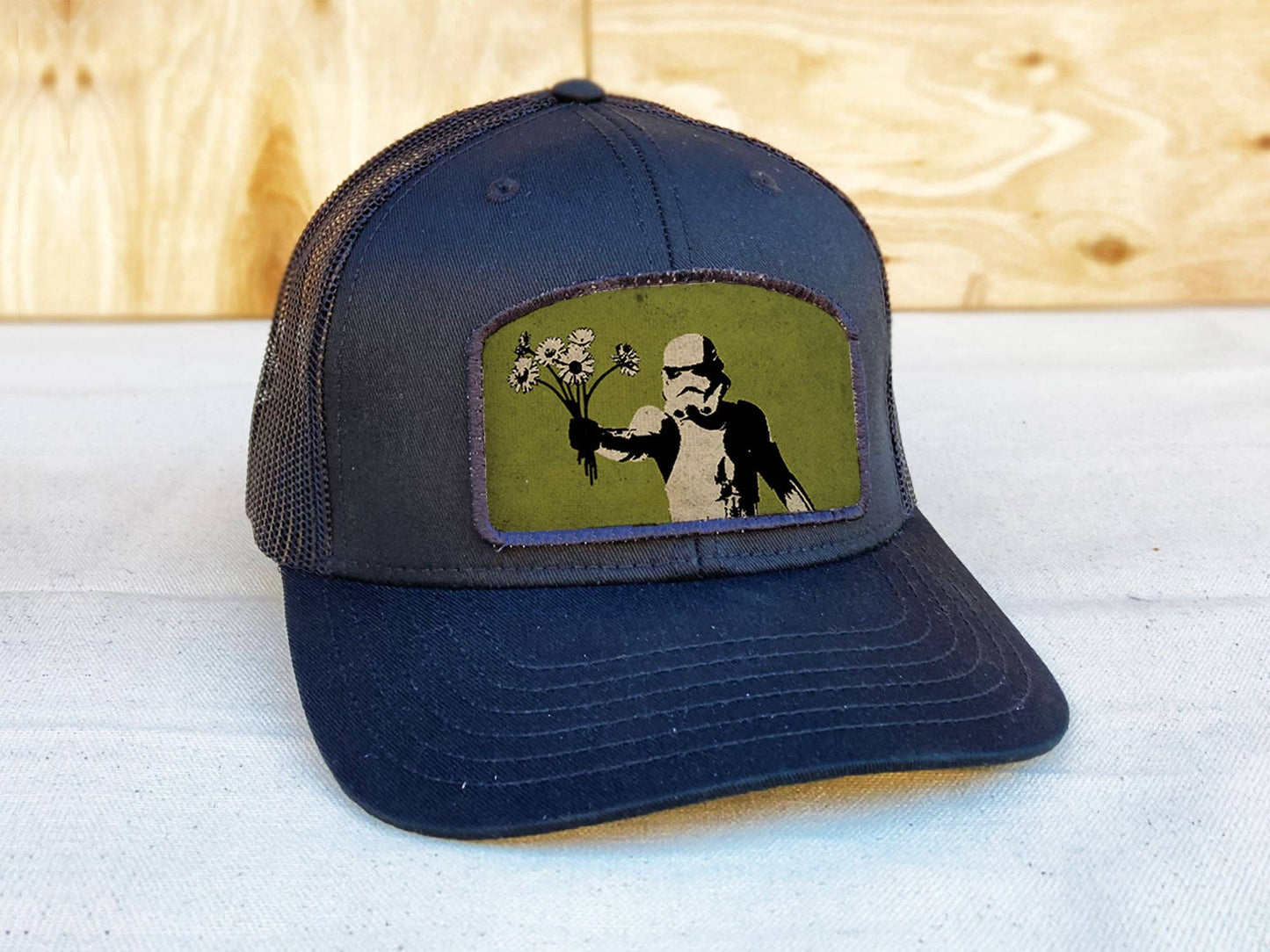 Navy blue cap with a graphic of a stormtrooper holding flowers on a light blue surface.