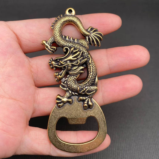 Brass dragon-shaped bottle opener held in a hand against a dark background