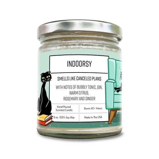 Candle jar with a label featuring the word 'Indoorsy' and a cat and armchair illustration on a white background