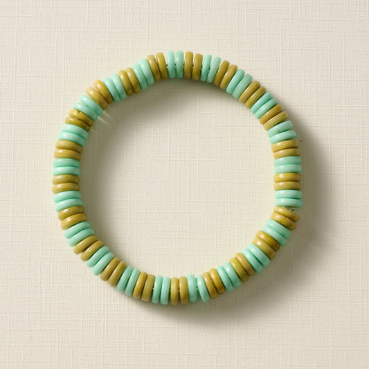 Beaded bracelet with green and olive beads on a beige background