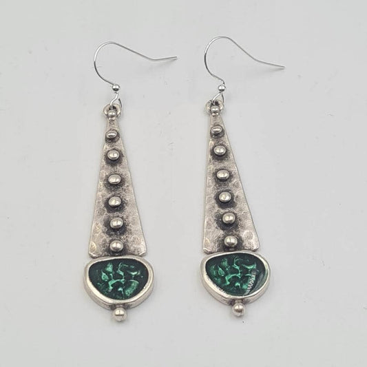 A pair of silver dangle earrings with textured triangular drops, small metallic beads, and oval green inlay details, shown on a plain light gray background.