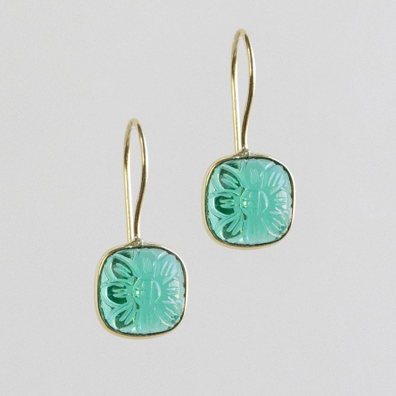 Pair of earrings with green floral designs on a light gray background