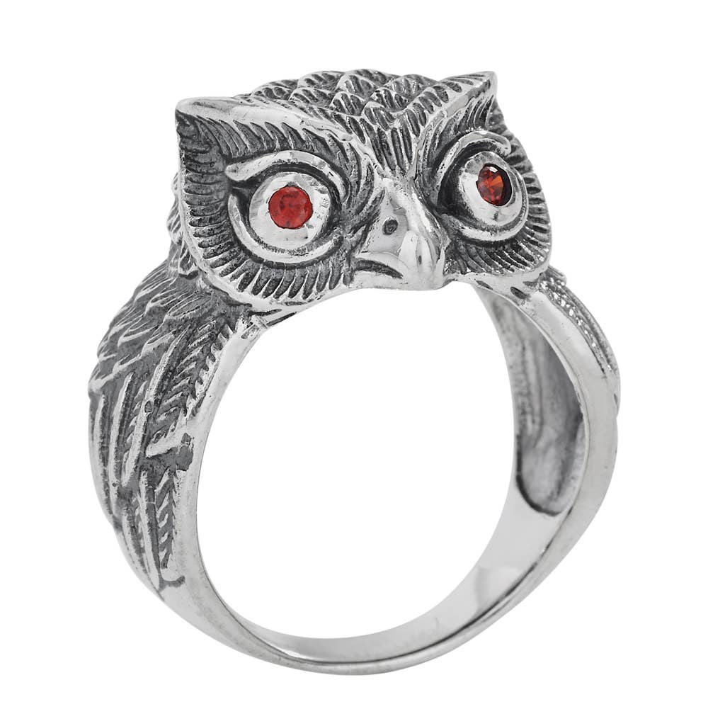 A sterling silver owl ring with detailed feather engravings and small red gemstone eyes, shown on a plain white background.