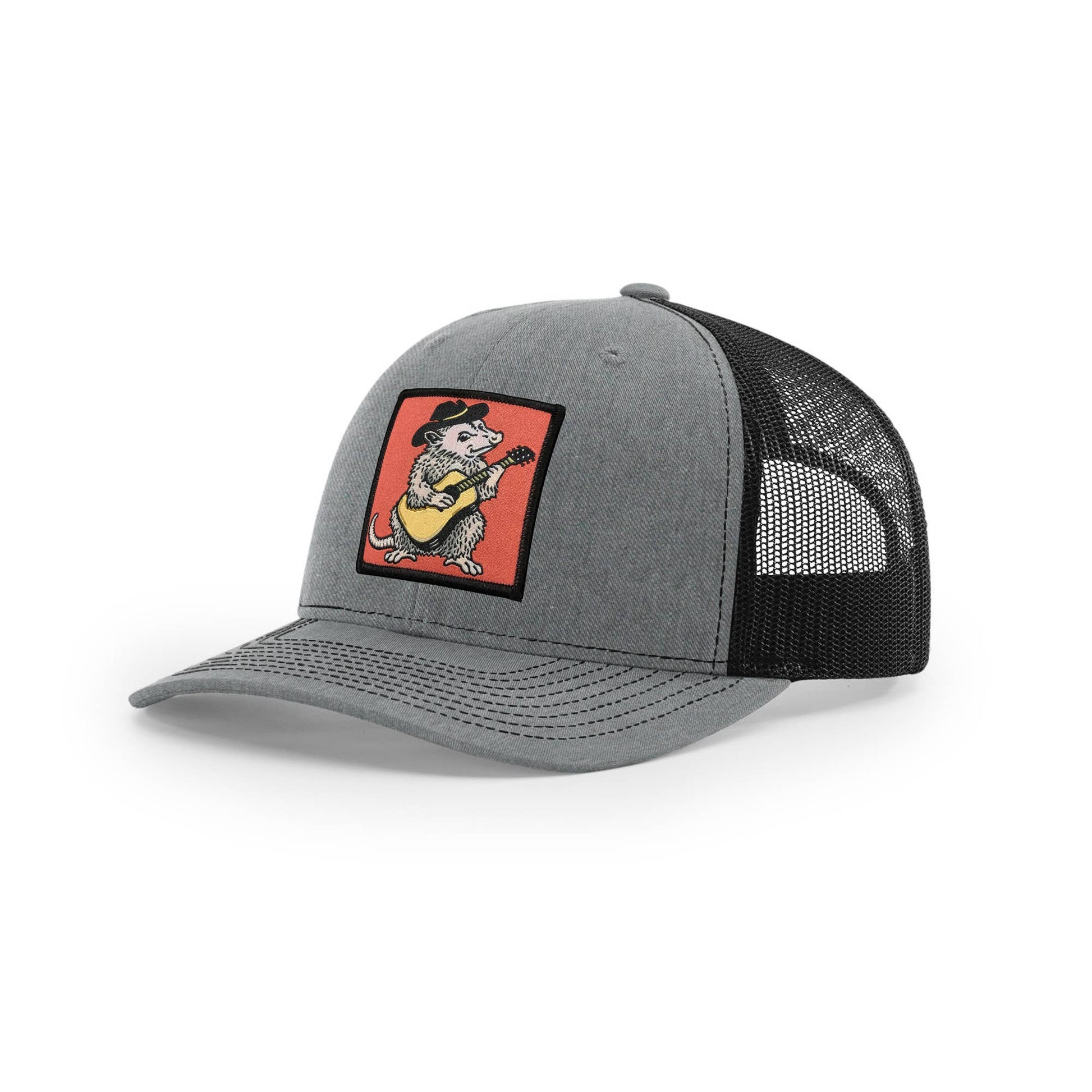 Gray and black trucker hat with a mesh back and colorful opossum plating the guitar patch, on a white background.