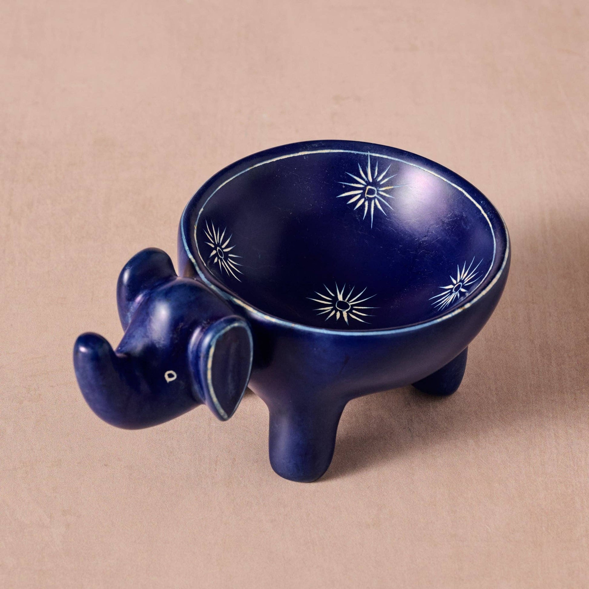 Blue ceramic elephant ring dish with star patterns on a beige background