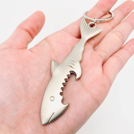 Shark-shaped bottle opener keychain held in a hand against a white background