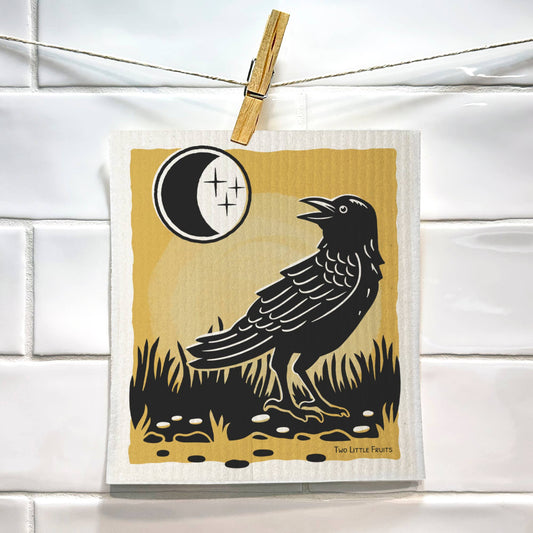 Swedish dish cloth with a black crow design hanging on a line.