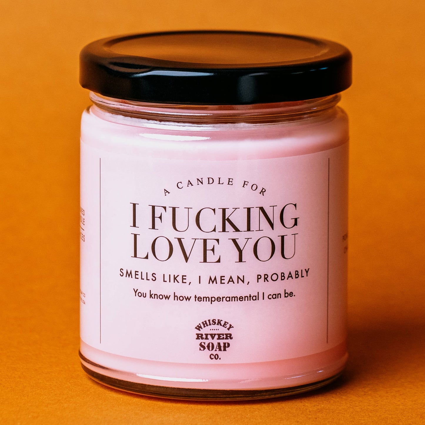 Pink candle with a humorous label on an orange background