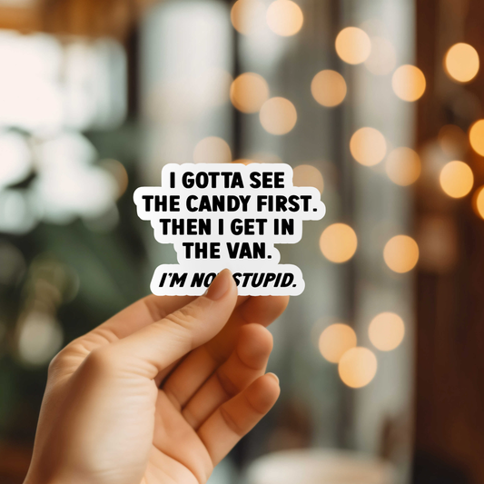 Hand holding a sticker with humorous text in front of blurred lights