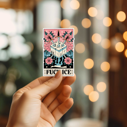 Hand holding a sticker with floral design, swords, and text against a blurred background