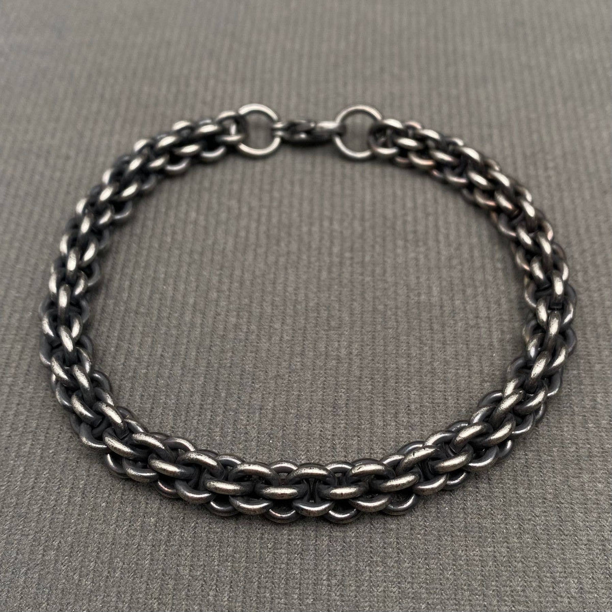 Black chain bracelet on a gray fabric background