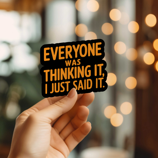 Hand holding a sticker with text 'Everyone was thinking it, I just said it.' against a blurred background