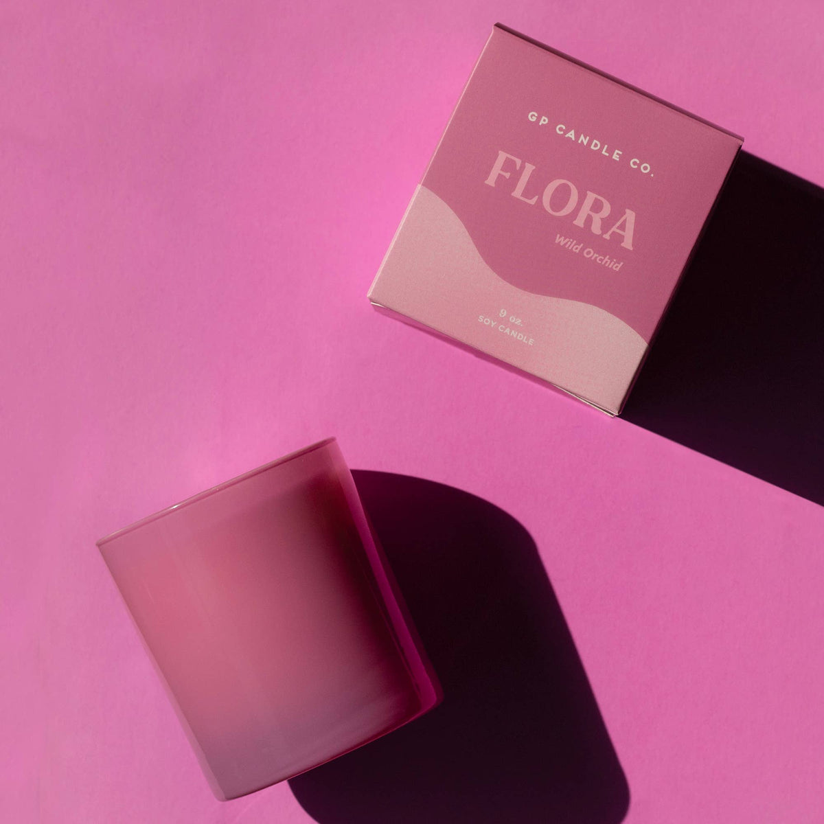 Pink candle and box with 'Flora' branding on a pink background