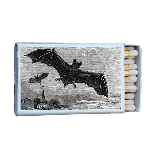 Matchbox with illustration of bats flying over a cityscape on a white background