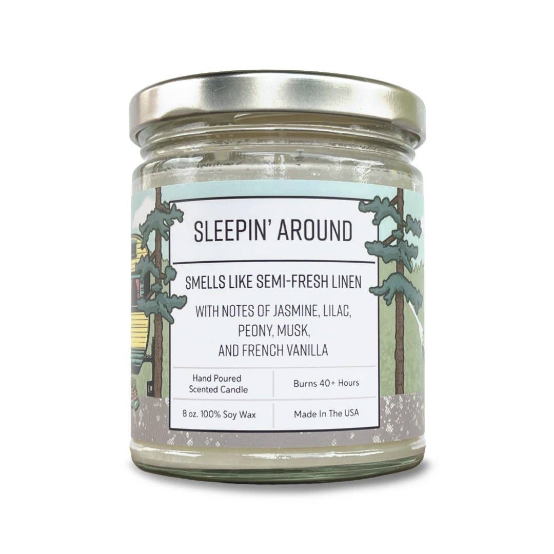 Scented candle jar labeled 'Sleepin' Around' with a trees on the label on a white background