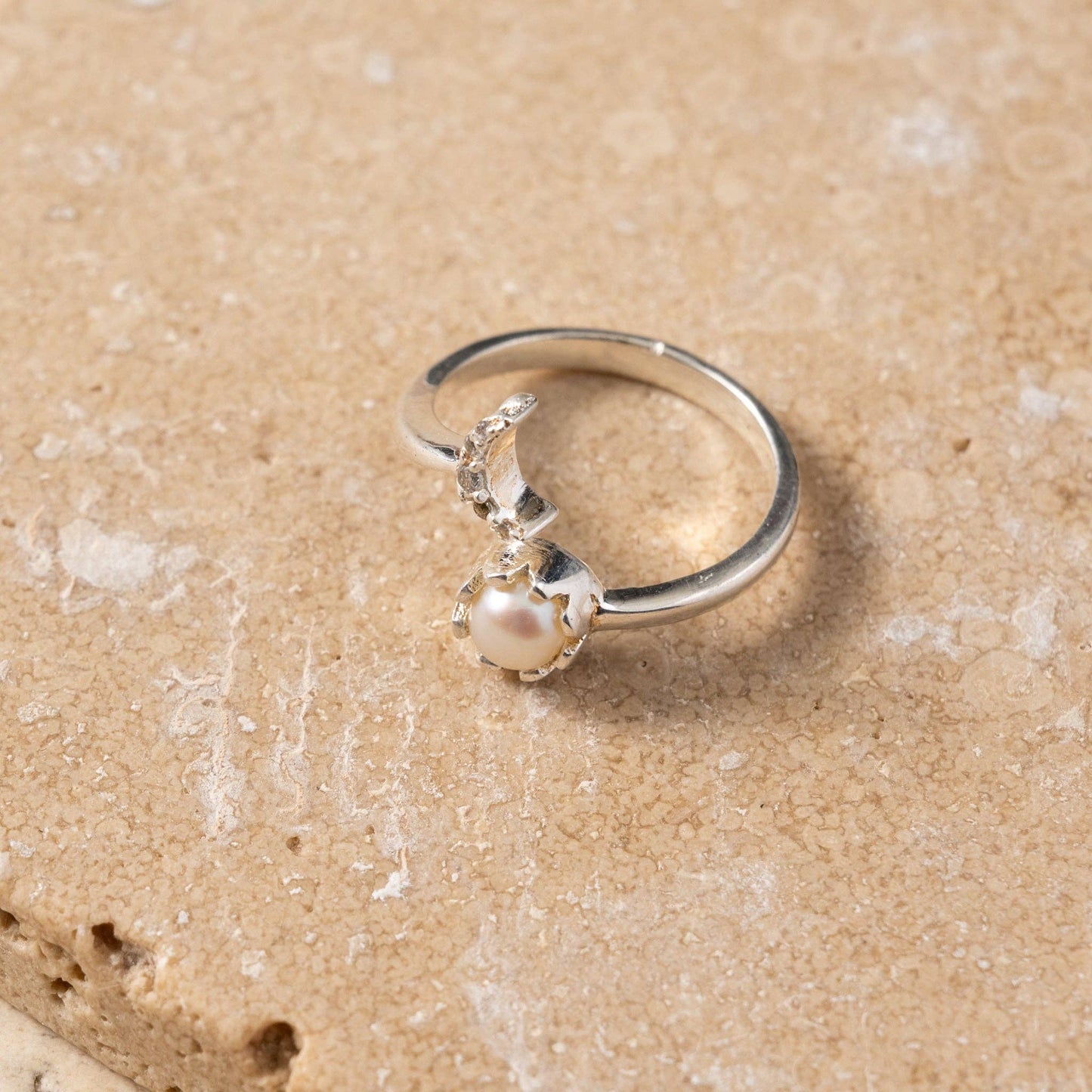 Silver ring with a pearl on a sandy background