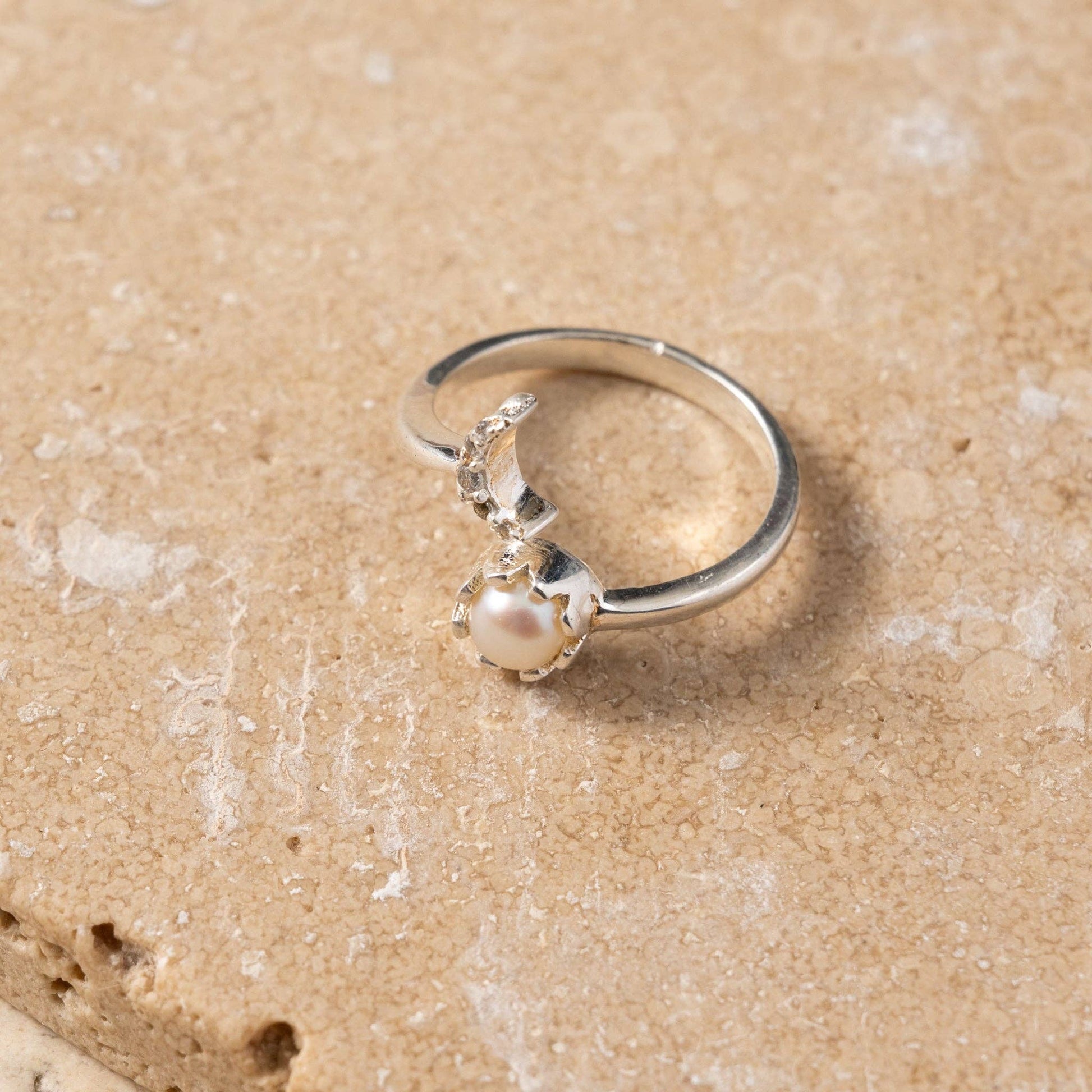 Silver ring with a pearl on a sandy background