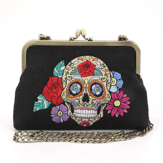 Black handbag with colorful skull and floral design on a white background