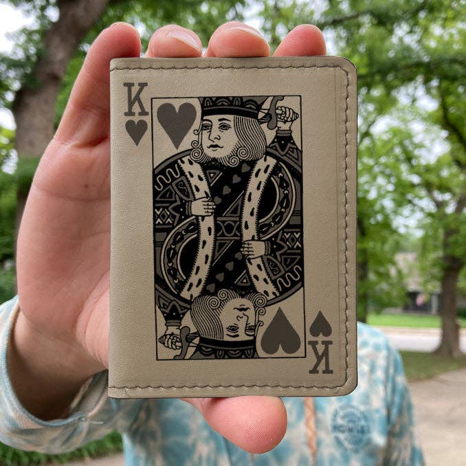 Hand holding a Wallet with a King of Hearts design against a blurred outdoor background