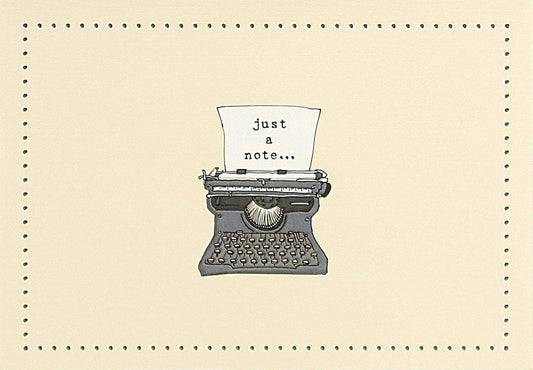 Vintage typewriter with a piece of paper reading 'just a note...' on a notecard with a beige background