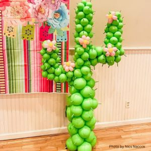 Festive Balloon cactus sculpture decoration in a room with colorful wall and wooden floor.