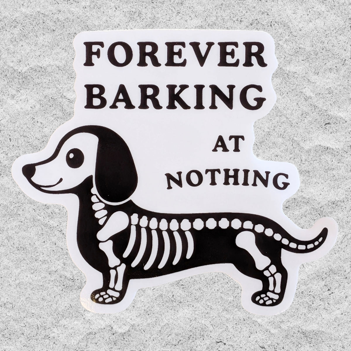 A die-cut vinyl sticker featuring a black and white dachshund skeleton with the text 'FOREVER BARKING AT NOTHING' in bold black lettering, displayed on a textured gray background.