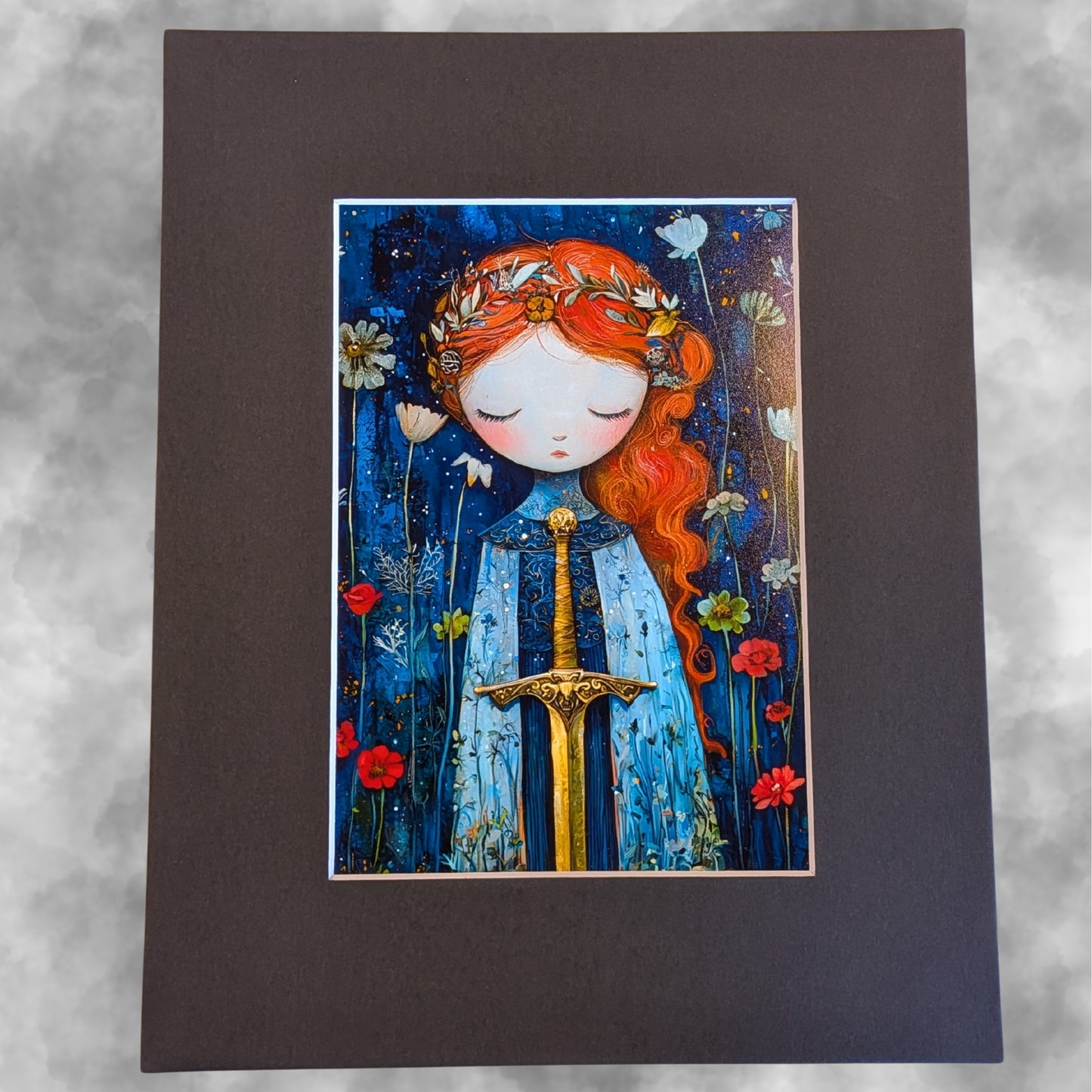 A rectangular art print featuring a whimsical illustration of a girl with long red hair, closed eyes, and a blue dress, holding a gold sword, surrounded by wildflowers on a dark blue background. The print is mounted on a wide, dark mat against a light gray textured backdrop.