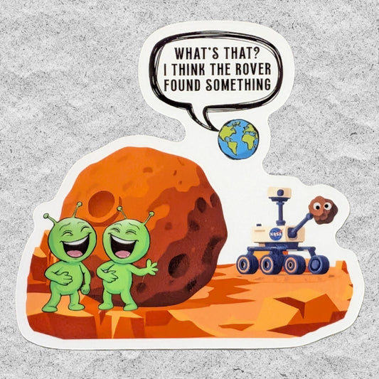 A die-cut sticker featuring two laughing green aliens and a Mars rover on an orange Mars landscape, with a speech bubble reading 'WHAT'S THAT? I THINK THE ROVER FOUND SOMETHING' and a small Earth illustration.