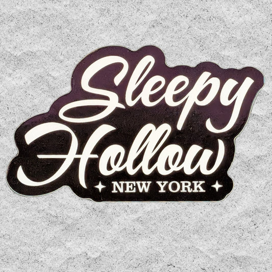 A die-cut sticker with the text "Sleepy Hollow NY" on a textured grey background.