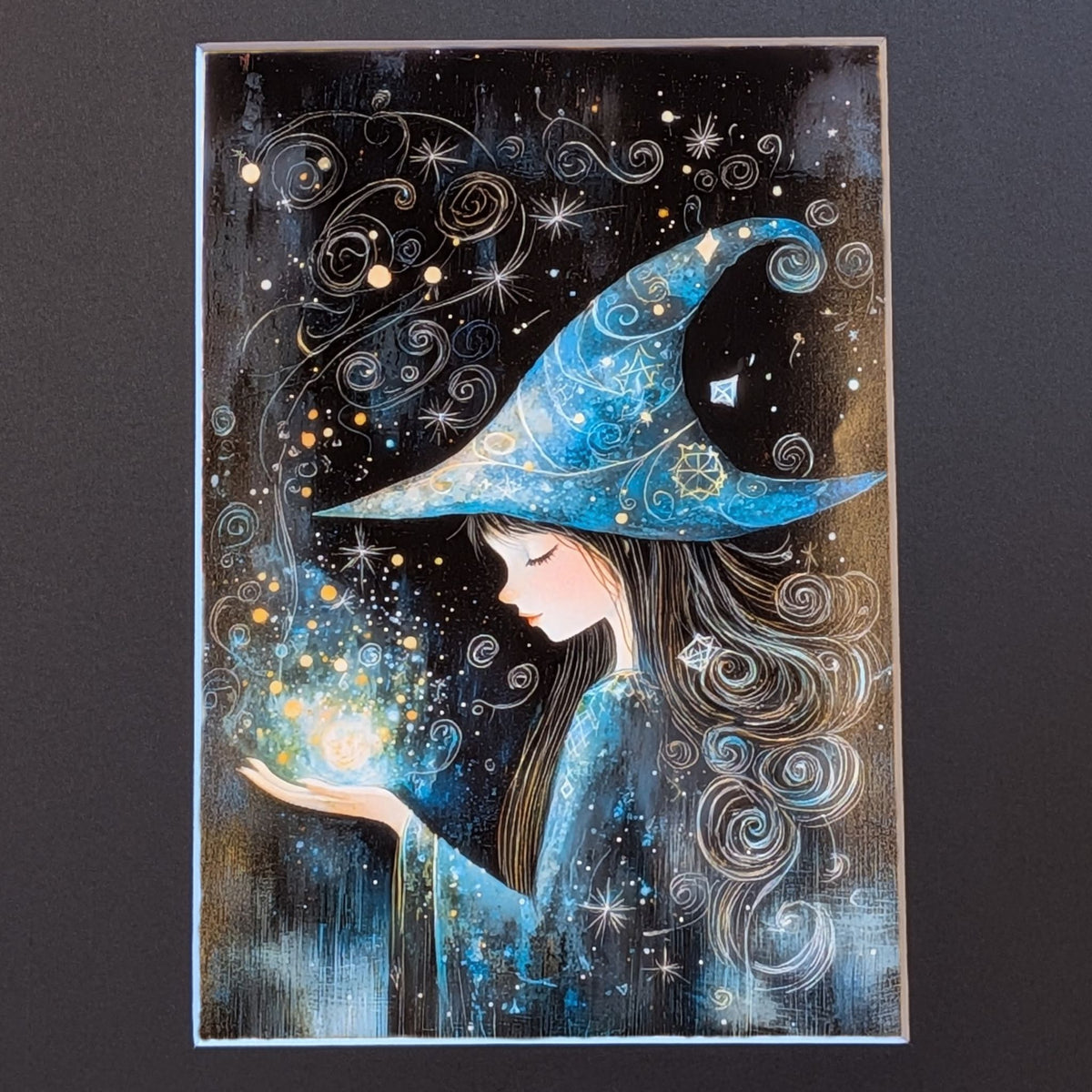 A vertical fantasy art print depicting a young witch in profile wearing a large blue starry hat and holding a glowing orb, set against a dark starry sky. The print is shown against a dark gray background.