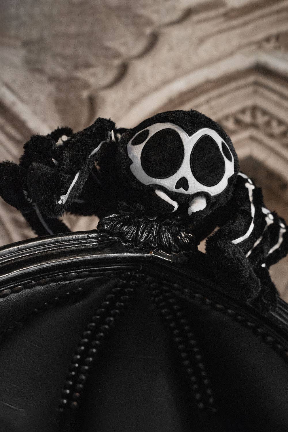 Black skeleton spider against a textured beige background