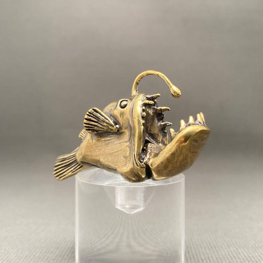Brass Lantern fish figurine on a clear stand against a gray background
