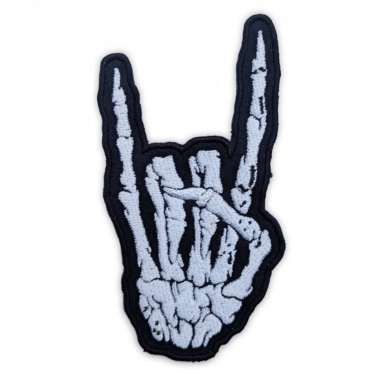 Skeleton hand embroidered patch making a rock-on gesture on a white background