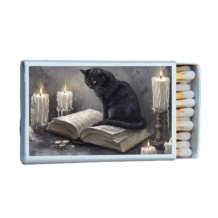 A decorative matchbox with a gothic illustration of a black cat sitting on an open book surrounded by melting candles, with several matches visible in the open right side.