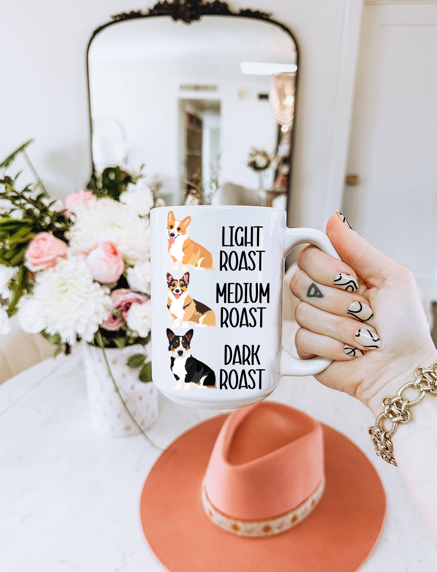 Hand holding a mug with Corgi dog illustrations and text "Light Roast, Medium Roast, Dark roast"
