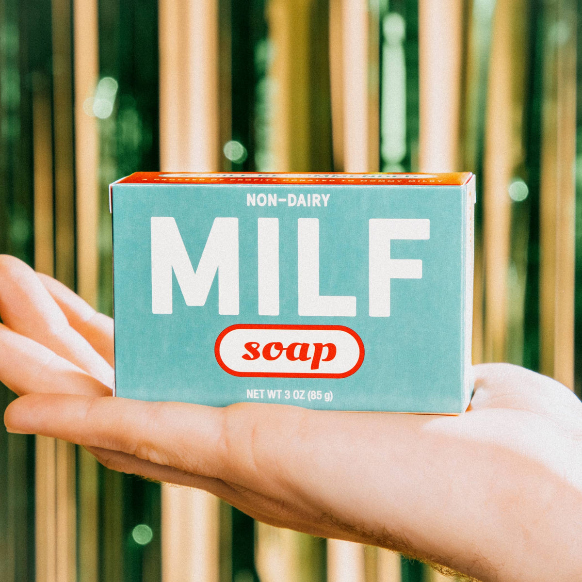 Box of 'MILF soap' held by a hand with a bamboo background