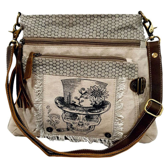 Beige handbag with skull design and brown leather straps on a white background