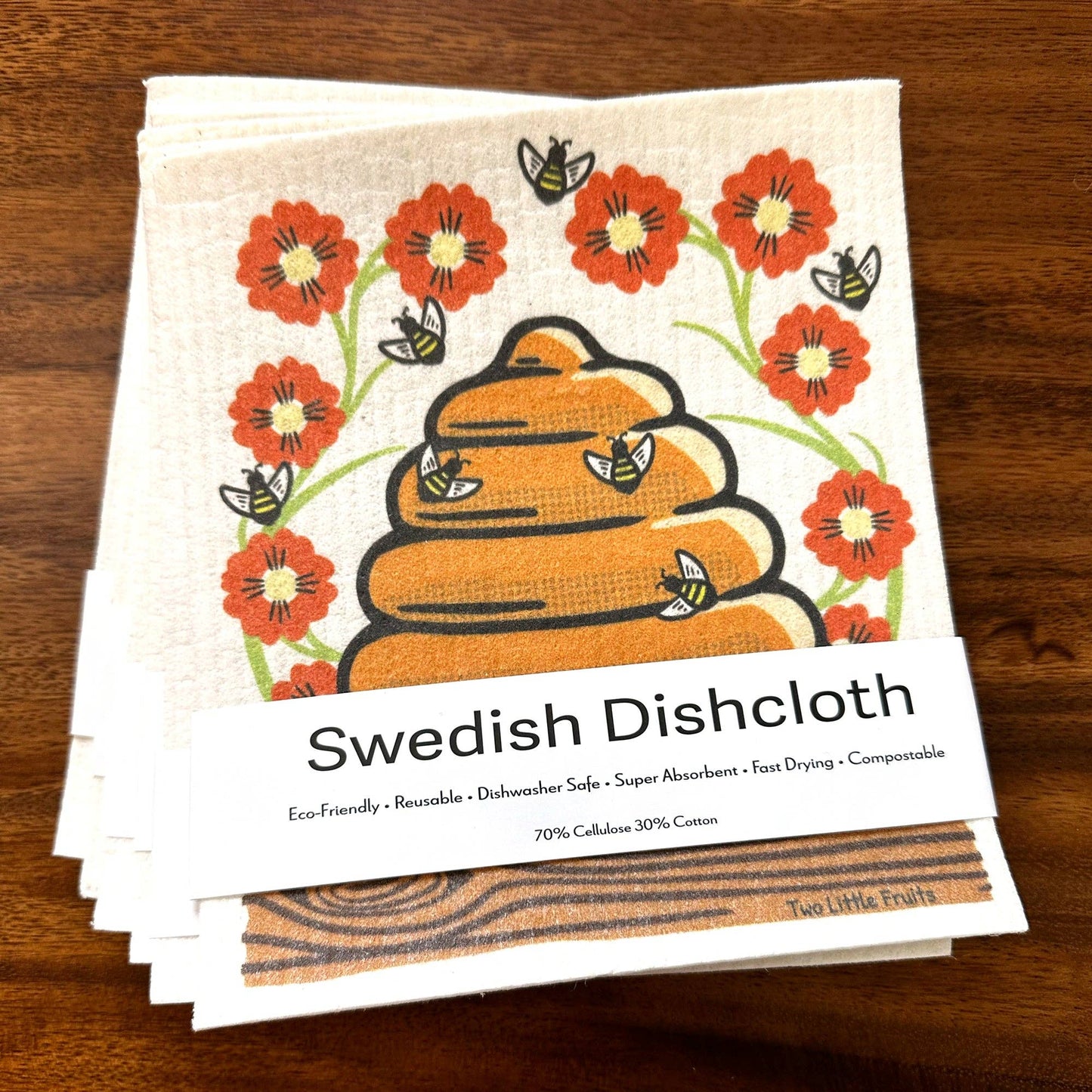 Stack of Swedish Dishcloths with floral and bee  with beehive design on a wooden surface