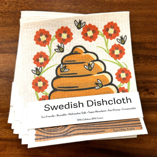 Stack of Swedish Dishcloths with floral and bee  with beehive design on a wooden surface