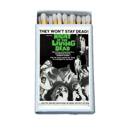 A novelty matchbox styled like a vintage movie poster for the film 'Night of the Living Dead'. The matchbox is open, showing white match heads with yellow tips, and the front features the movie poster artwork with the title in green text.