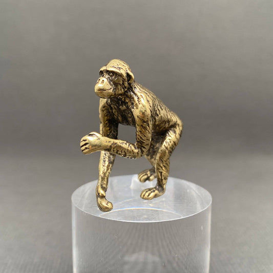 Brass Orangutan figurine on a clear stand against a gray background