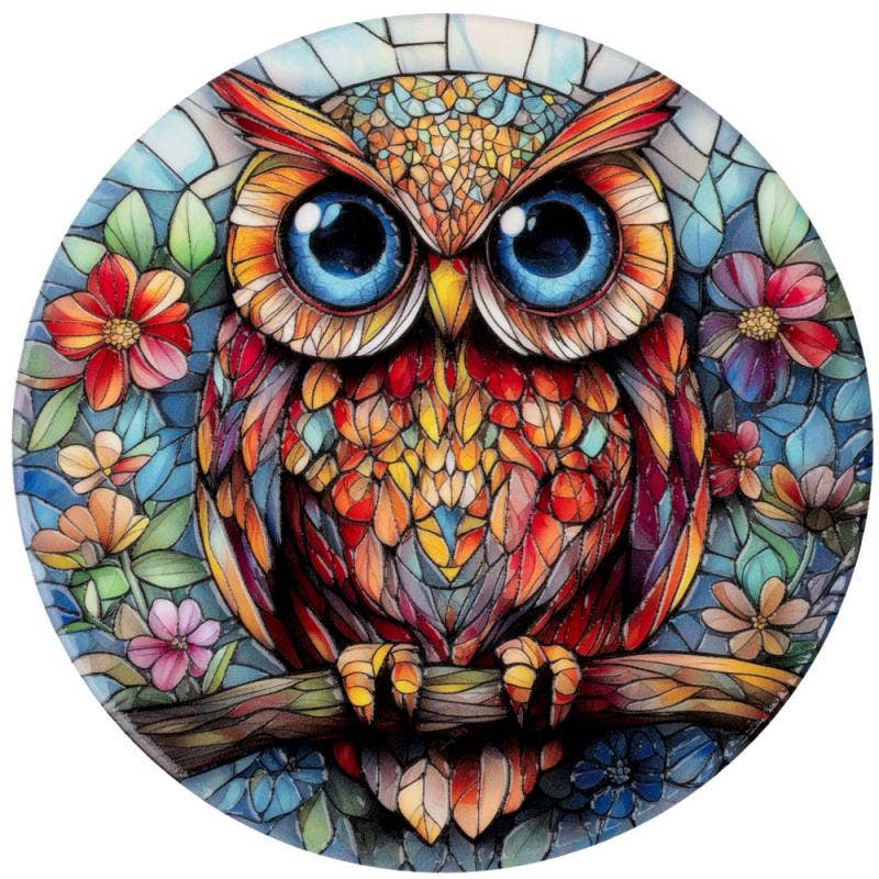 A circular stained-glass-style coaster of an owl with large blue eyes, orange and red patterned feathers, and colorful flowers around it on a white background.