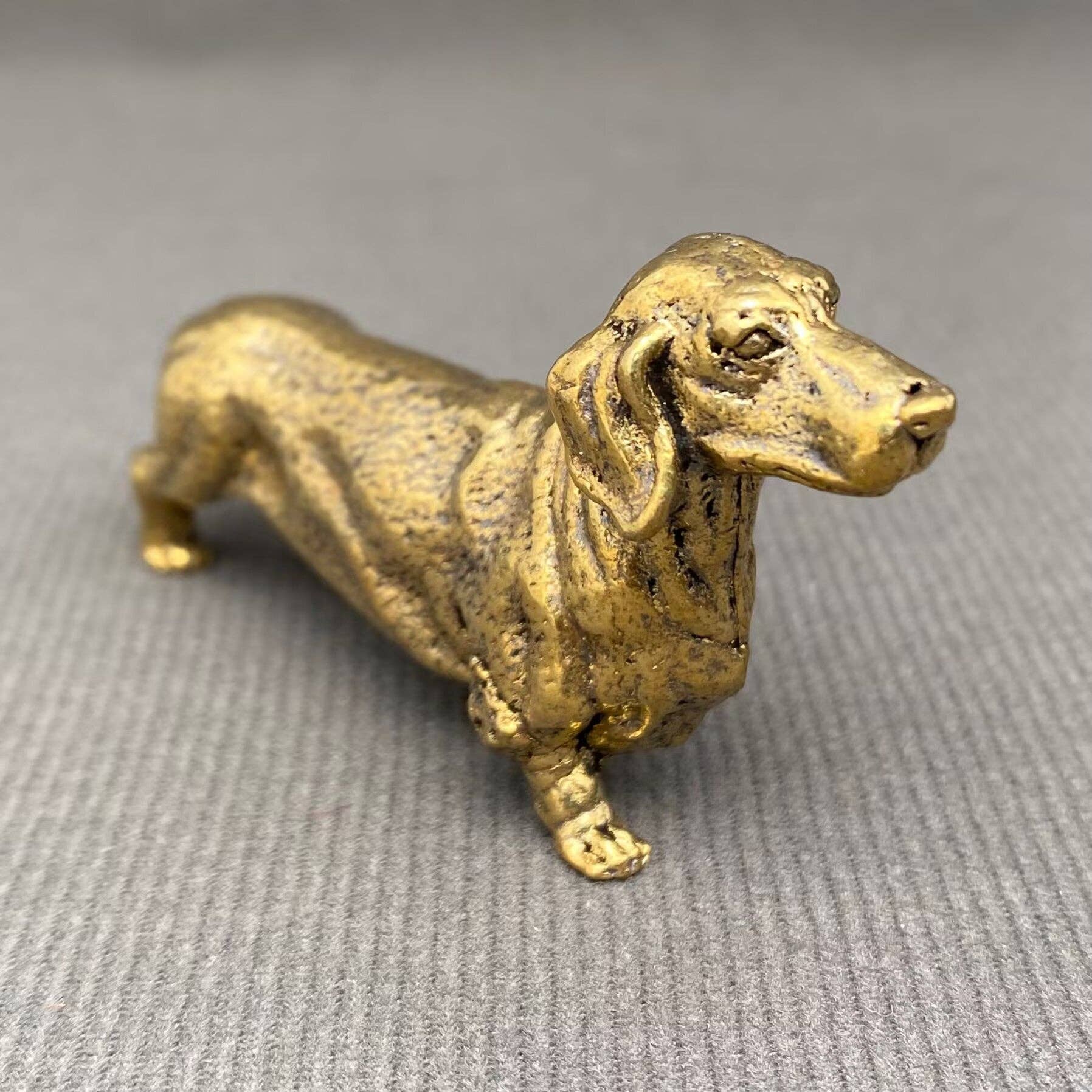 Brass figurine of a dachshund on a gray background