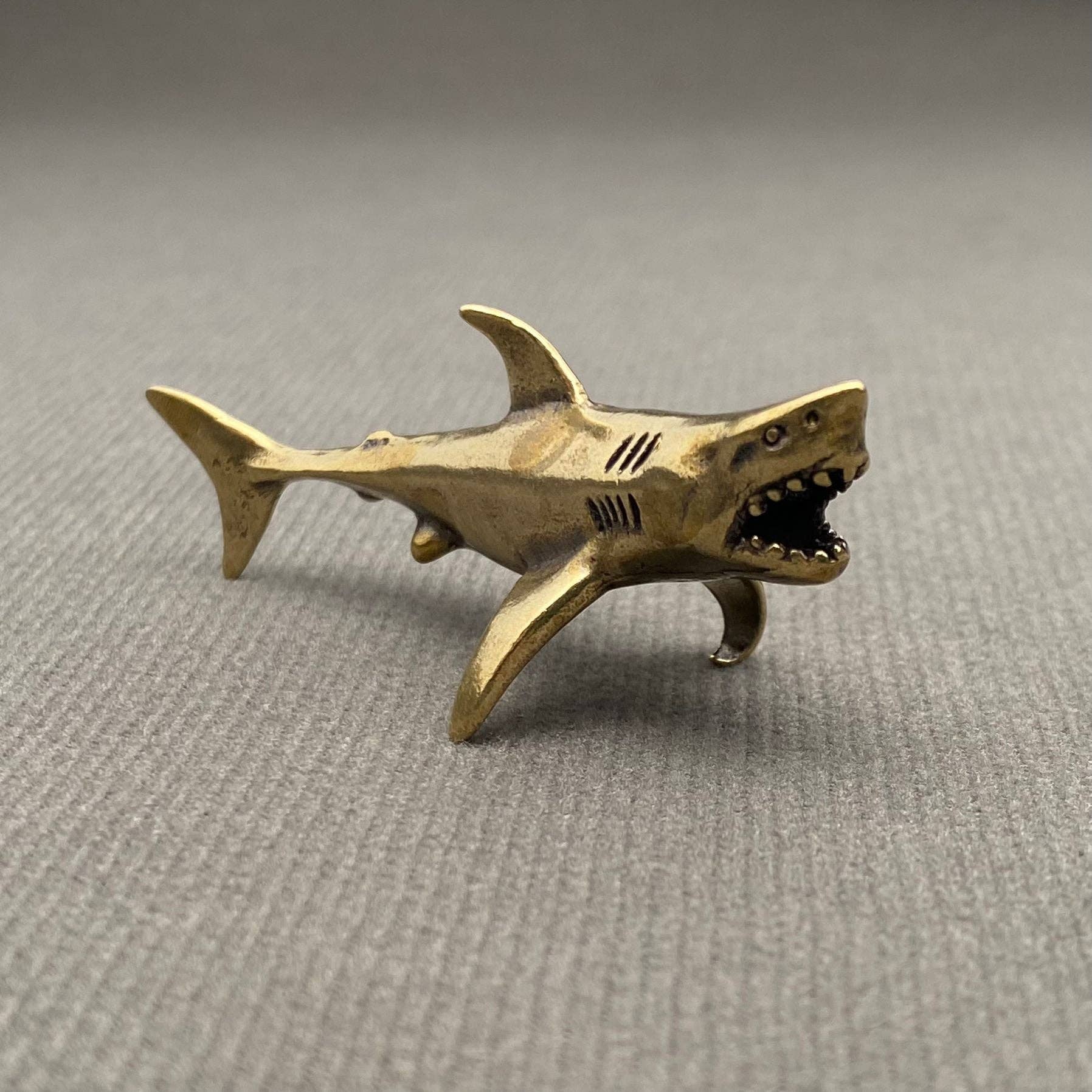 Brass shark figurine on a gray background