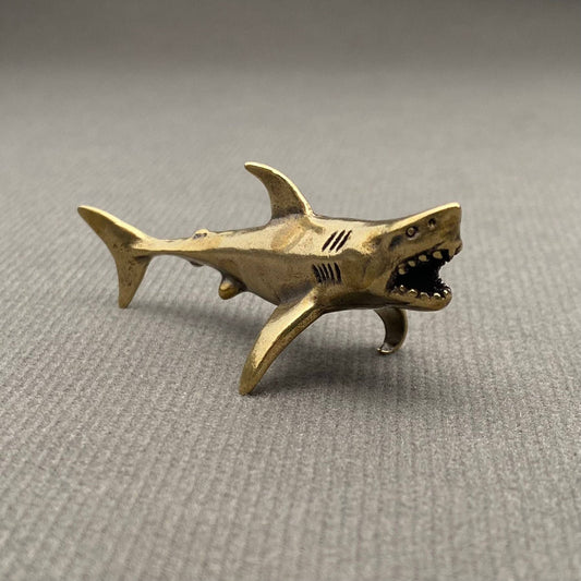 Brass shark figurine on a gray background
