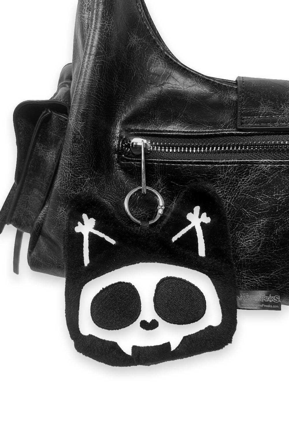 A plush black skull keychain charm with white embroidered details and a silver metal ring.