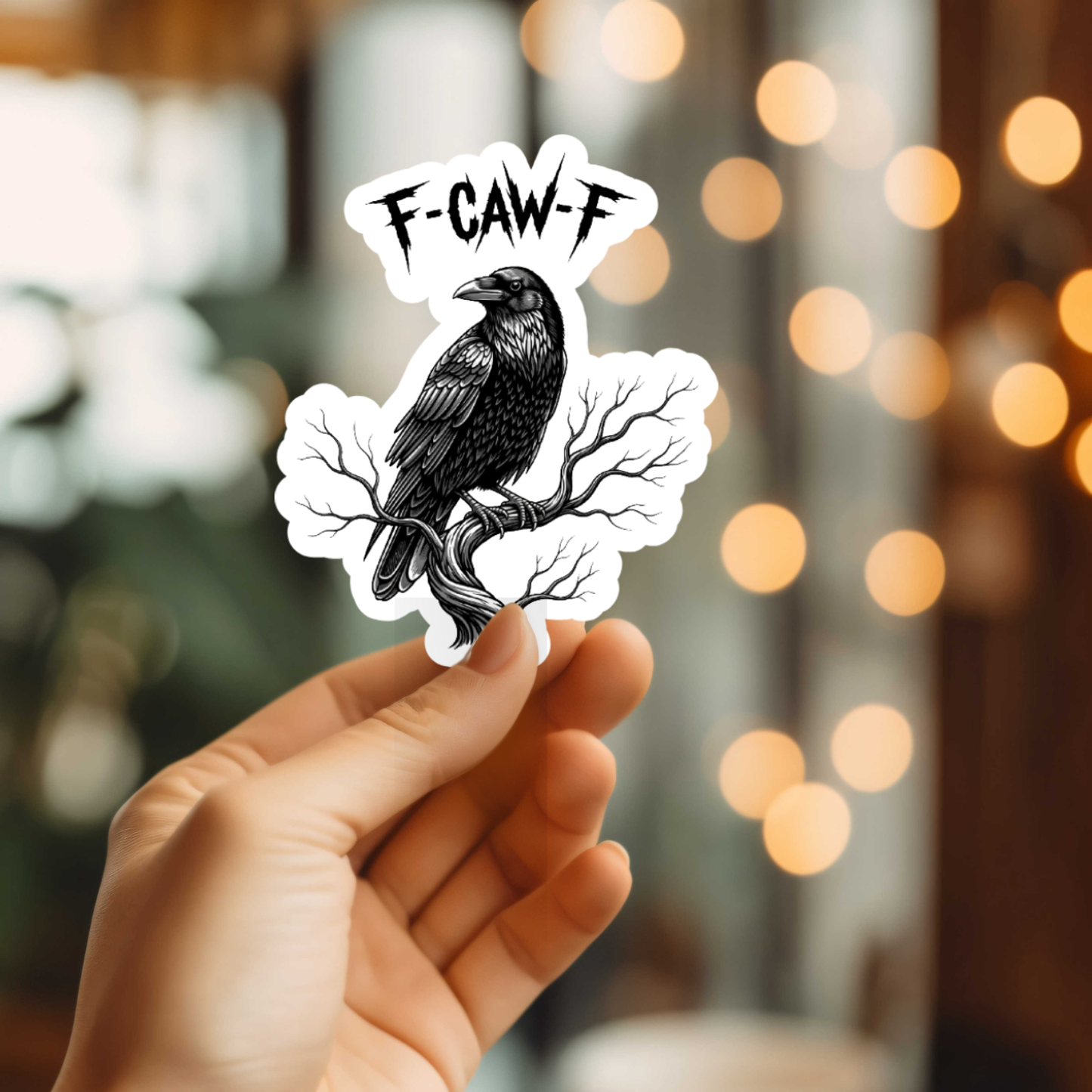 Hand holding a sticker with a black crow and 'F-CAW-F' text against a blurred background.