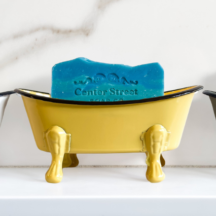 Colorful soap holder shaped like bathtubs on a marble countertop.